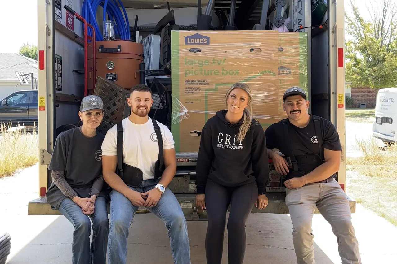 The GRIT Property Solutions moving crew sitting on the back of a loaded moving truck in Lubbock